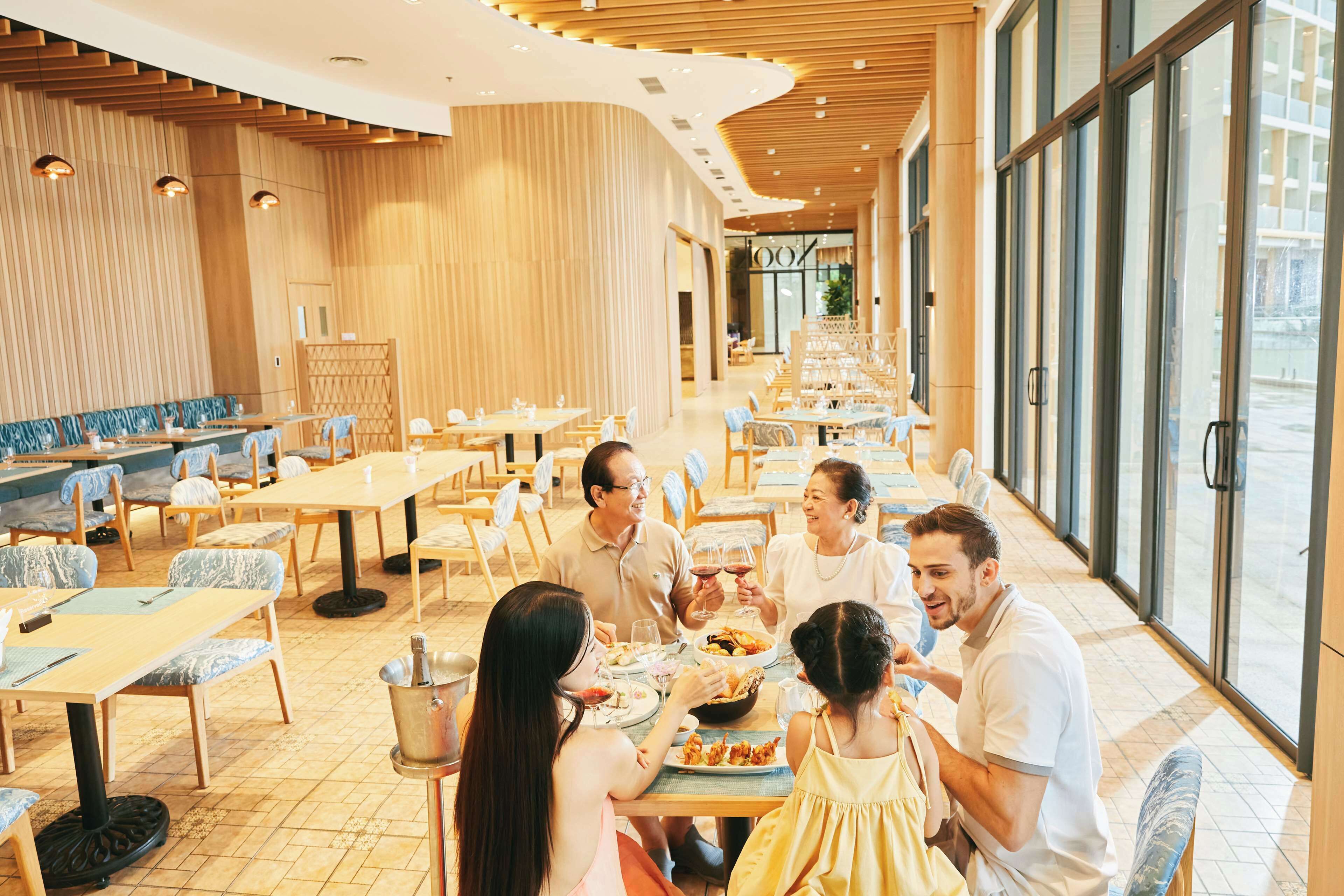 Een ruim restaurant met lange tafels en stoelen, grote ramen en een modern interieur.
