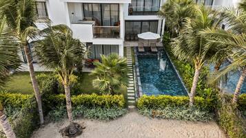 Um hotel moderno com piscina no terraço, rodeado por palmeiras e vegetação exuberante.