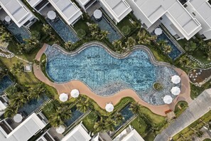 An aerial view of a resort with a large central pool, surrounded by palm trees and white buildings. - Angsana Ho Tram (Ho Chi Minh City)