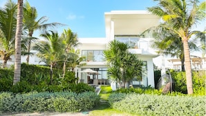 A modern two-story building with a glass facade, surrounded by lush greenery and palm trees. - Angsana Ho Tram (Ho Chi Minh City)
