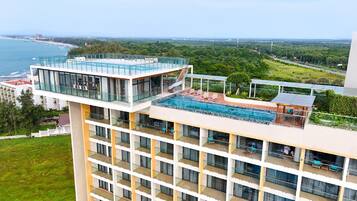 A high-rise hotel with a rooftop pool and a view of the sea.