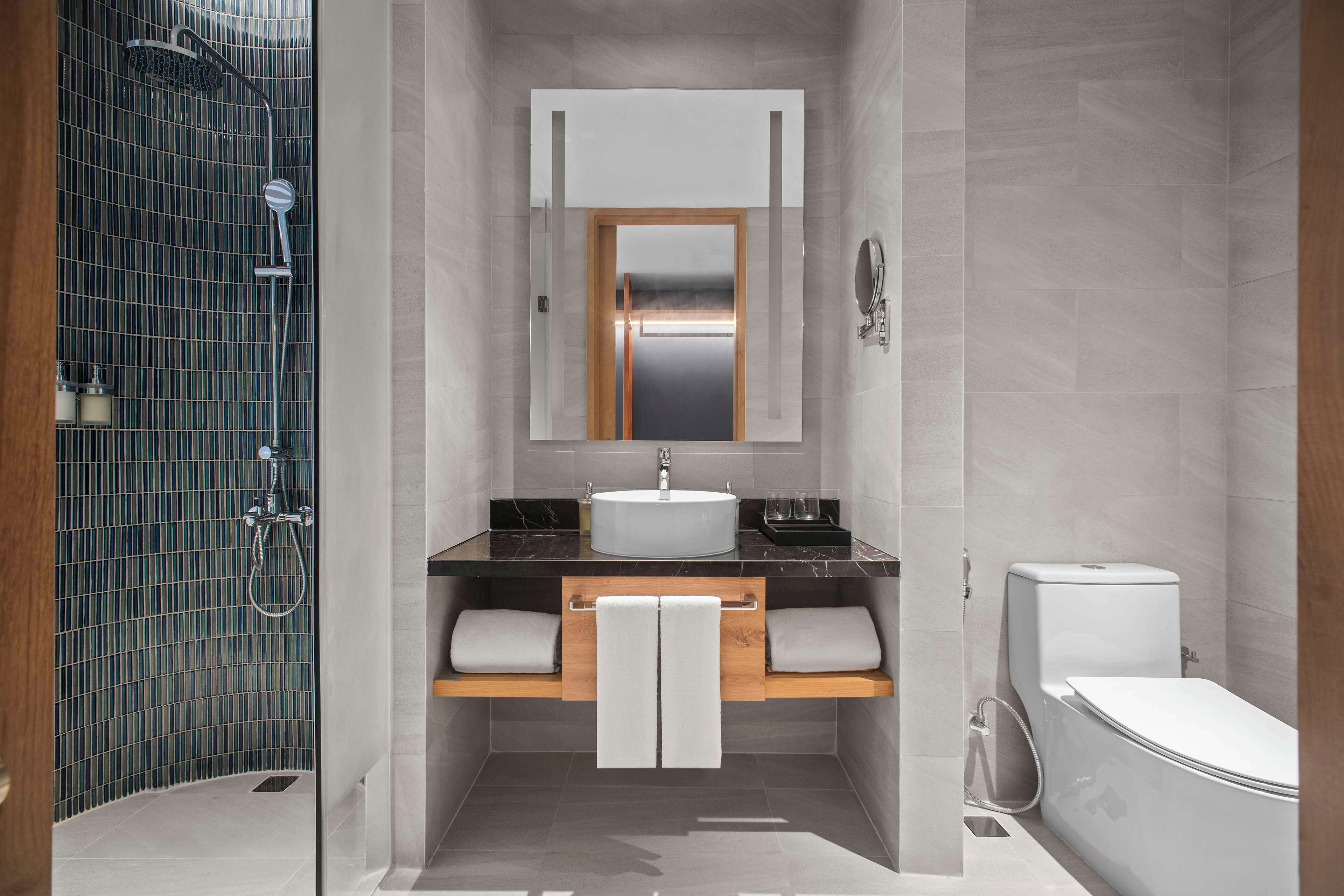 Un baño moderno con ducha de vidrio, tocador con lavamanos y un inodoro.