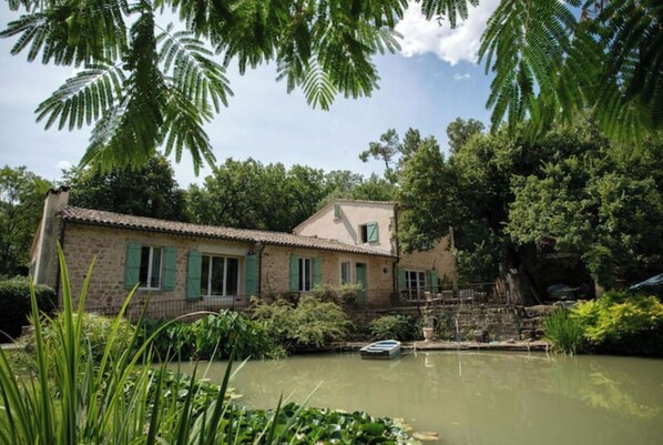 A rustic stone house with a small pond and a boat.