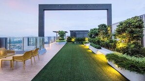Eine Dachterrasse mit Rasenfläche, Sitzgelegenheiten und Pflanzen.