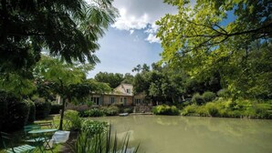 Una casa con uno stagno antistante, immersa nel verde.