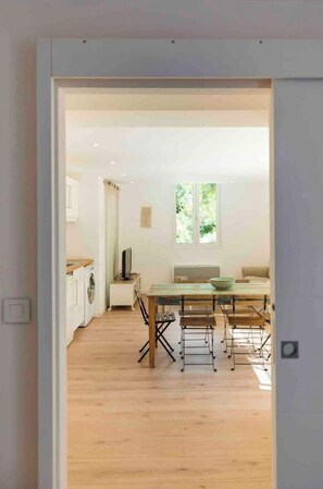 A modern kitchen with a wooden countertop, a washing machine, and a dining area with a table and chairs.