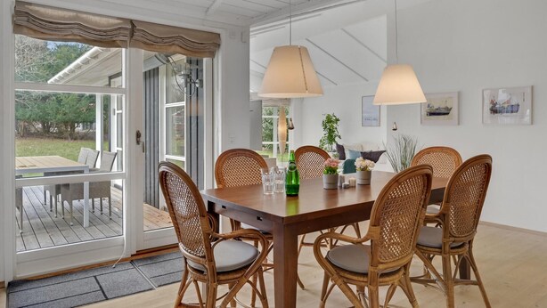 Un comedor con mesa de madera, sillas de mimbre e iluminación colgante.