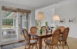 A dining area with a wooden table, wicker chairs, and pendant lights. - Cozy home in Hornbæk with kitchen (Hornbæk)