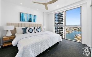 Relax in a spacious room with a large bed, a nightstand, and a window offering a view of the city and water.