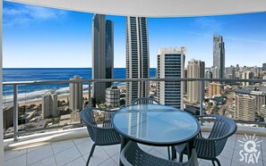 Enjoy a panoramic view of the coastal cityscape from this balcony, overlooking the beach and high-rise buildings.