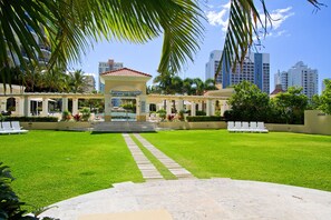 Relax in the serene courtyard, surrounded by lush greenery and palm trees, with a central gazebo and lounge chairs.