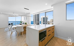 Enjoy ocean views from the spacious living area with a central kitchen island, dining table, and comfortable seating.