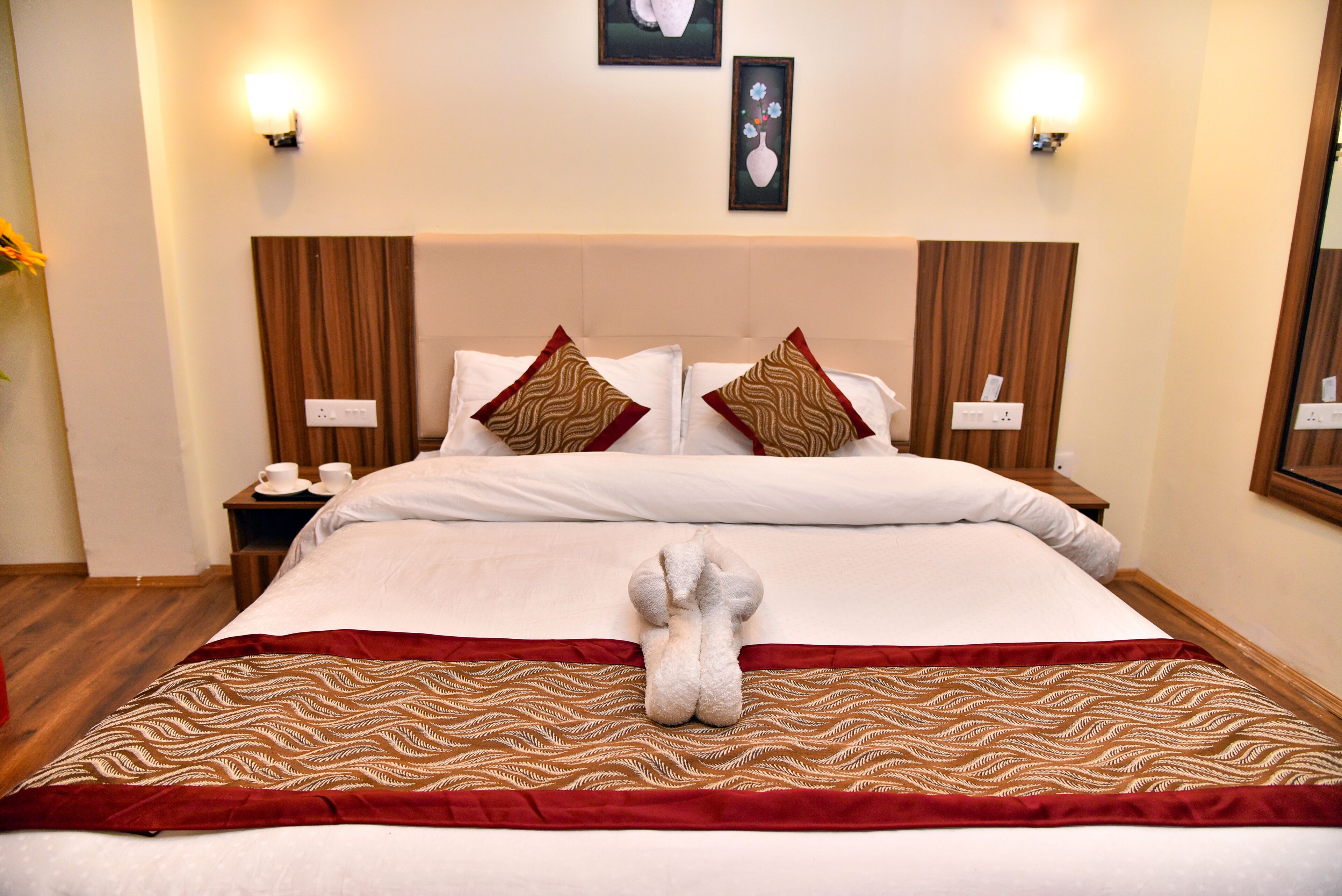A neatly made bed with a decorative towel, a wooden headboard, and bedside tables with lamps.