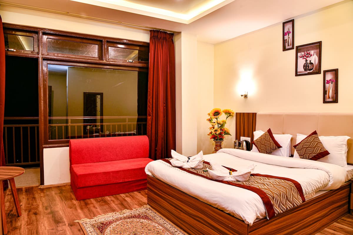 A hotel room with a wooden bed, red sofa, and a large window with curtains.