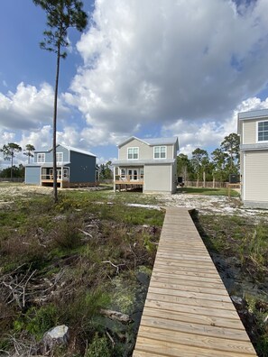 A residential area with a wooden deck leading to a house with a porch.