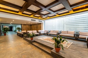 A spacious lobby with a long sofa, a patterned rug, and potted plants. - Hotel Lo Mustang (Kathmandu)