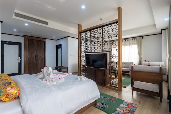 A hotel room with a bed, a television, a wooden partition, a sofa, and a chair. - Hotel Lo Mustang (Kathmandu)