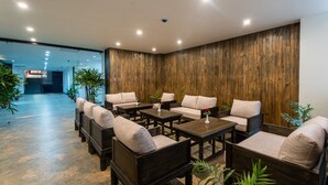 A lobby with dark wooden paneling, multiple seating areas with cushioned chairs and tables, and potted plants. - Hotel Lo Mustang (Kathmandu)
