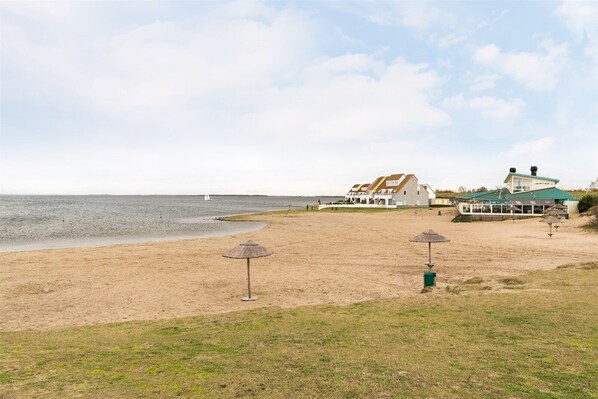 A beachside property with a large house, a dining area, and a view of the sea.