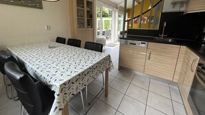 Un comedor con una mesa preparada para cuatro, una cocina con armarios de madera y vistas al exterior.