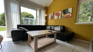 Una sala de estar moderna con un sofá negro, una mesa de centro de madera y arte abstracto en la pared.
