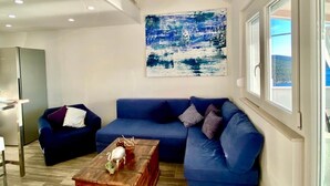 Un saló modern amb un sofà seccional blau, una taula de centre de fusta i un quadre abstracte gran a la paret.