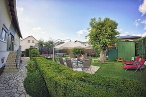 Enjoy outdoor dining under the shade of a tree and a large umbrella in this patio area.