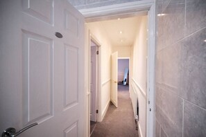 Enter a classic hallway leading to a room with a door and a large window.