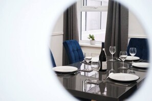 Enjoy a meal for four at this elegant dining area, complete with a table set and a bottle of wine.