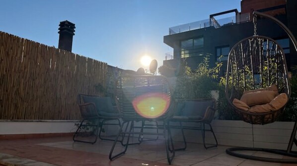 Une terrasse avec une clôture en bois, un fauteuil suspendu et une table avec des chaises.