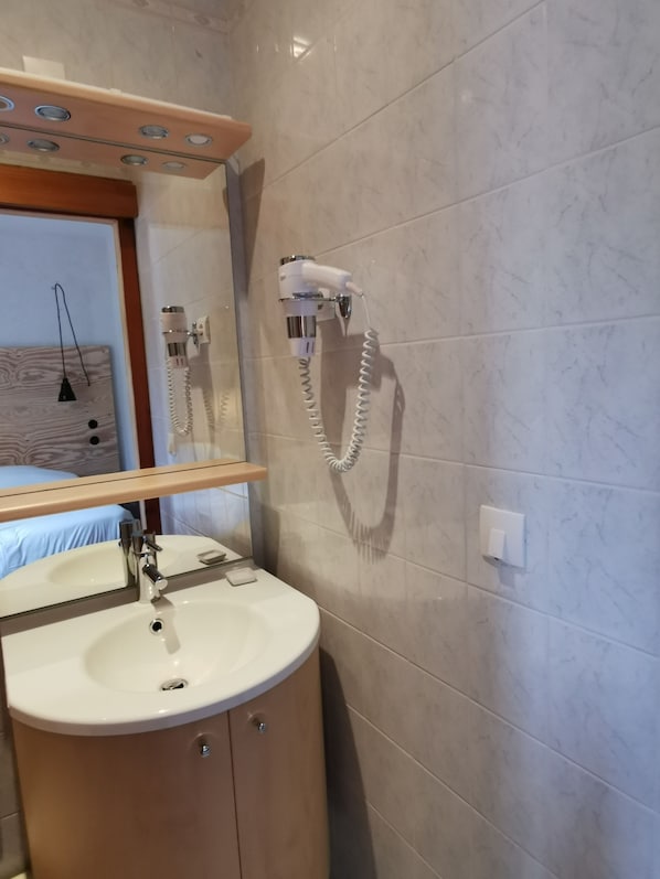 A bathroom with a sink, mirror, and a hairdryer mounted on the wall. - Hostel Quartier Libre (Saint-Jean-en-Royans)