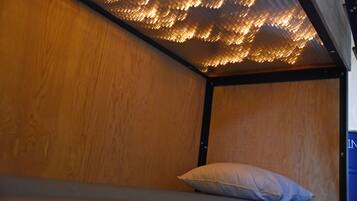Ein Stockbett mit Holzkopfstück und einem Kissen.