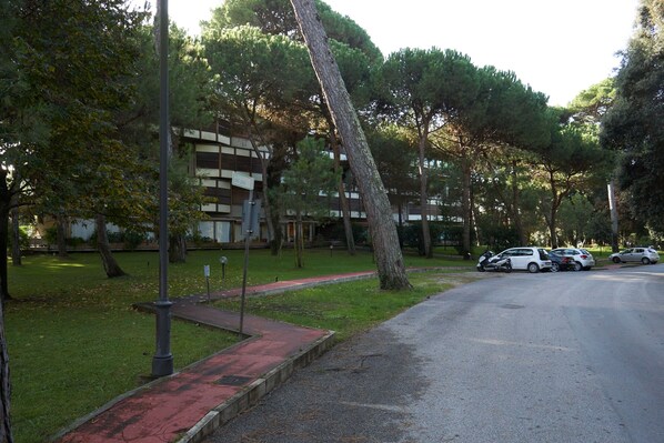 A street with parked cars, trees, and a building with a modern design.