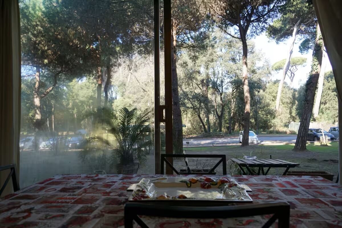 A dining area with a table set for two, overlooking a parking lot and trees.