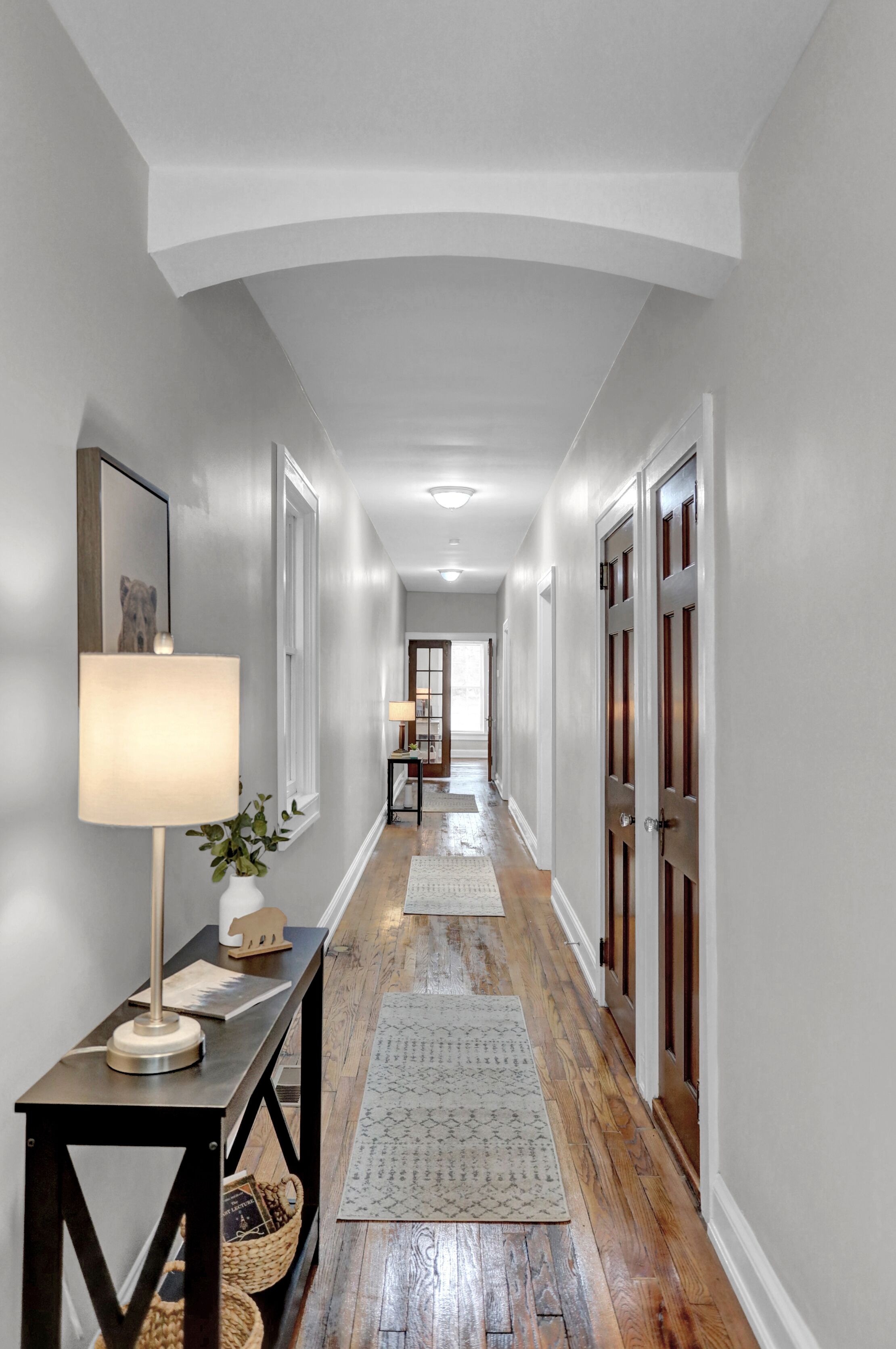 Elegant hallway with hardwood floors, cozy rugs, and warm lighting.
