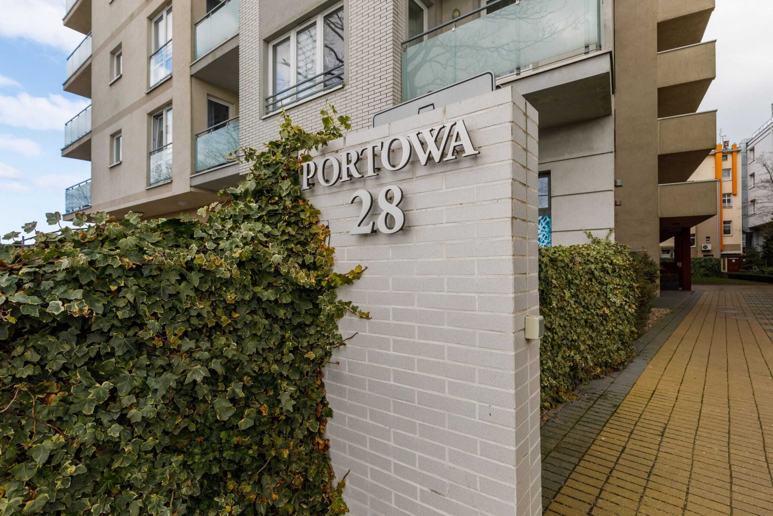 Un edificio con un cartel que dice "PORTOWA 28" y fachada de ladrillo.