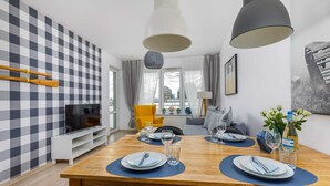 Ein moderner Essbereich mit karierter Wand, Holztisch und Pendelleuchten.