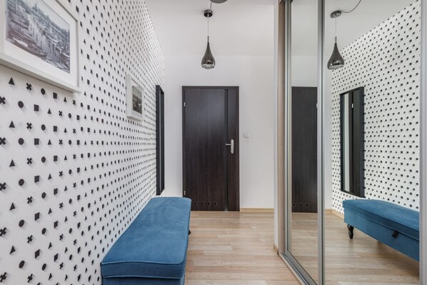 A hallway with patterned walls, a wooden floor, a blue bench, and a door.