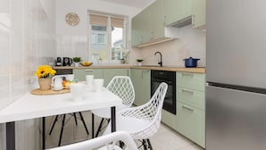 A modern kitchen with white cabinets, a dining table with chairs, and a window.