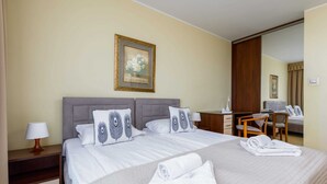Ein Hotelzimmer mit einem großen Bett, zwei Kissen mit Federmotiv, einem Schreibtisch, einem Stuhl und einem Spiegel.