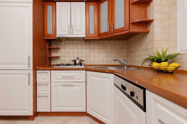 A kitchen with white cabinets, a wooden countertop, a sink, and a dish rack with lemons.