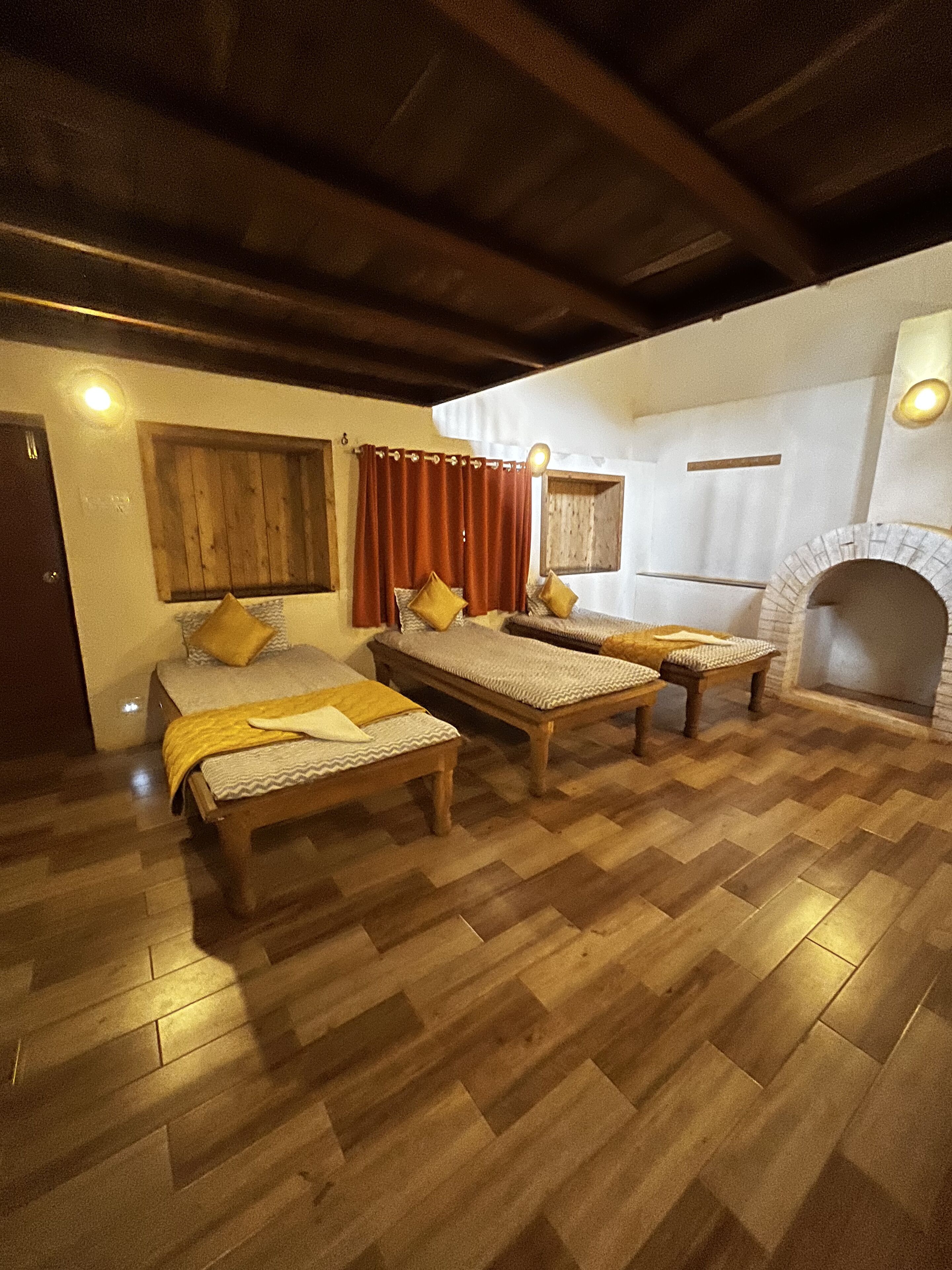 Quarto com três camas de madeira, lareira e soalho de madeira.