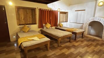 Quarto com três camas de madeira, lareira e soalho de madeira.
