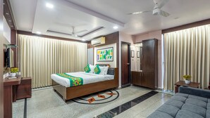 A modern hotel room with a bed, a sofa, a desk, and a wardrobe. - Treebo Marina Grand, Railway Station (Visakhapatnam)