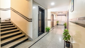 A modern hotel lobby with a marble staircase, elevators, potted plants, and a clean, well-lit interior. - Treebo Marina Grand, Railway Station (Visakhapatnam)