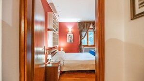A bedroom with a bed, bedside table, lamp, and a window with curtains.
