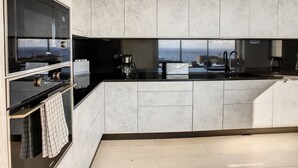 Una cocina moderna con armarios grises, encimera negra y vistas al mar.