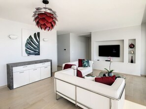 Un salon moderne avec un canapé, un téléviseur et des œuvres d’art accrochées au mur.