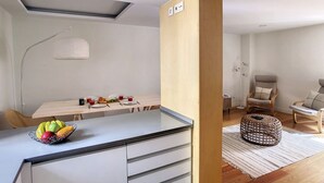 Eine moderne Küche mit Essbereich, Holzboden und einer gemütlichen Sitzecke mit Stühlen und einem runden Teppich.