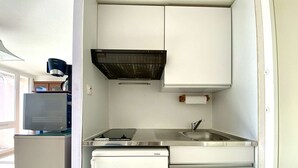 Eine kompakte Küchenzeile mit Spüle, Herd und Kühlschrank.